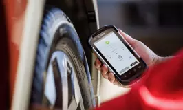 Tire technician inspecting a tire with a handheld device
